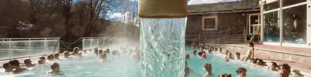 Baignade dans les eaux thermales des bains de Saint-Thomas sous un ciel bleu, avec de nombreux visiteurs profitant du bassin extérieur.