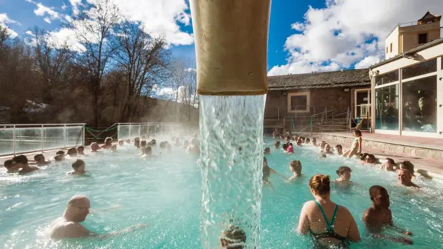 Baignade dans les eaux thermales des bains de Saint-Thomas sous un ciel bleu, avec de nombreux visiteurs profitant du bassin extérieur.