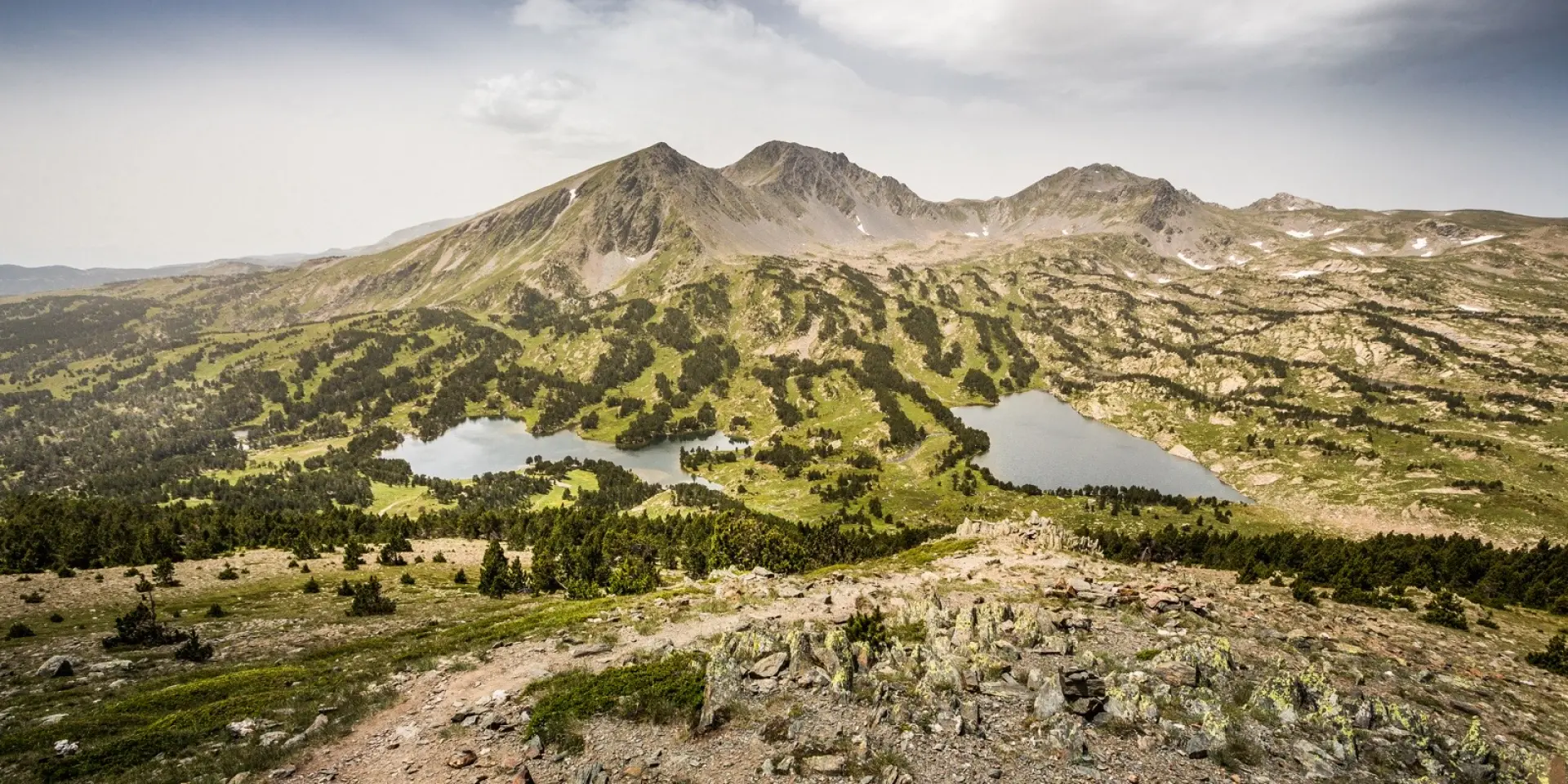 Vue panoramique sur les lacs et les reliefs du massif du Carlit, dans les Pyrénées catalanes, sous un ciel légèrement voilé.