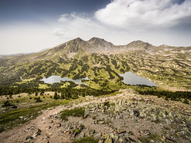 Vue panoramique sur les lacs et les reliefs du massif du Carlit, dans les Pyrénées catalanes, sous un ciel légèrement voilé.