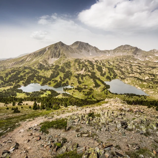 Vue panoramique sur les lacs et les reliefs du massif du Carlit, dans les Pyrénées catalanes, sous un ciel légèrement voilé.