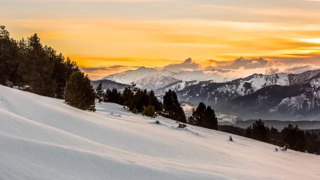 Lever de soleil sur le massif du Canigó et les Pyrénées, vu depuis le plateau enneigé de La Calme à Font-Romeu.
