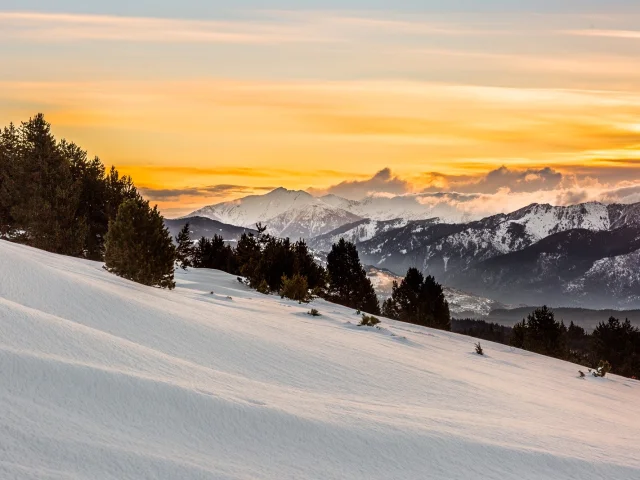 Lever de soleil sur le massif du Canigó et les Pyrénées, vu depuis le plateau enneigé de La Calme à Font-Romeu.