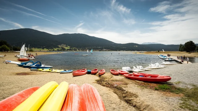 Activités nautiques sur la base du lac de Matemale en été, avec kayaks, pédalos et planches à voile au pied des montagnes du Capcir.