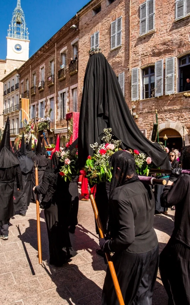 Procession religieuse de la Sanch à Perpignan, avec des pénitents vêtus de noir défilant dans les rues du centre historique.