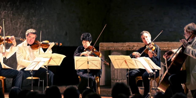 Ensemble de musiciens jouant des cordes — violons, alto et violoncelle — lors d’un concert de musique classique.