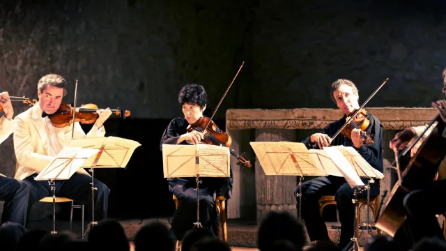 Ensemble de musiciens jouant des cordes — violons, alto et violoncelle — lors d’un concert de musique classique.