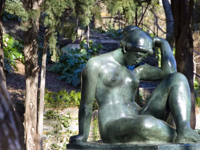 Sculpture en bronze représentant une femme assise, la tête penchée, dans le jardin du musée d’art moderne de Céret.