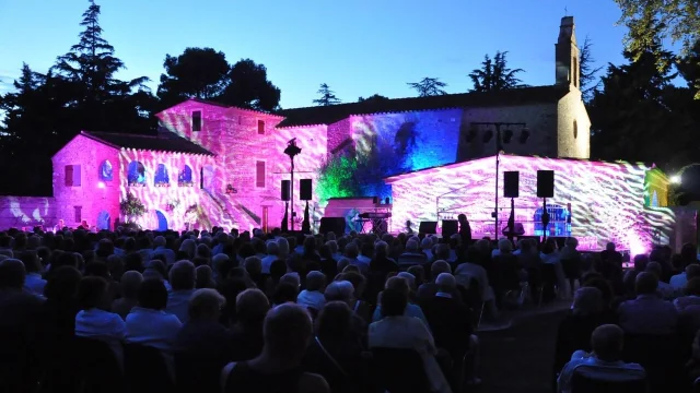 Spectacle nocturne en plein air projeté sur les façades illuminées d’un bâtiment en pierre, devant un public rassemblé dans les Pyrénées-Orientales.