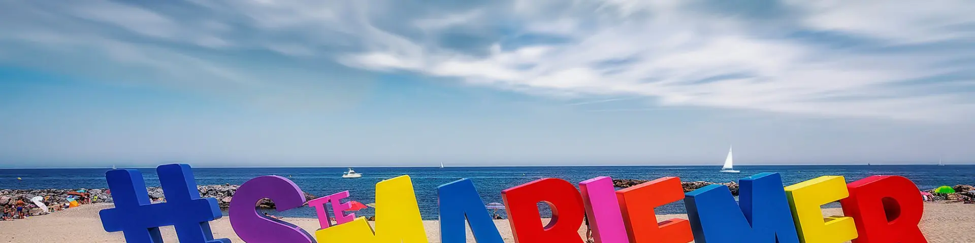 Installation colorée en forme de lettres géantes formant le mot « #STEMARIELAMER » sur la plage de Sainte-Marie-la-Mer, face à la Méditerranée.