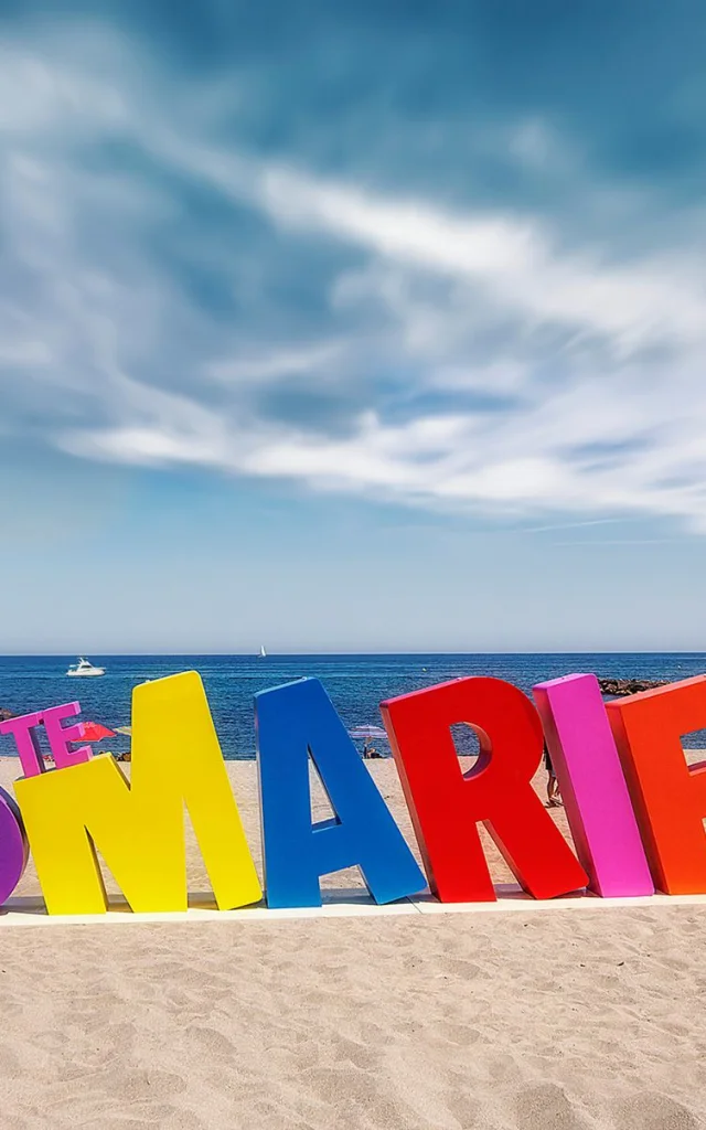 Installation colorée en forme de lettres géantes formant le mot « #STEMARIELAMER » sur la plage de Sainte-Marie-la-Mer, face à la Méditerranée.