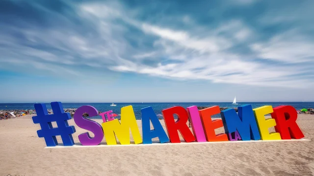 Installation colorée en forme de lettres géantes formant le mot « #STEMARIELAMER » sur la plage de Sainte-Marie-la-Mer, face à la Méditerranée.