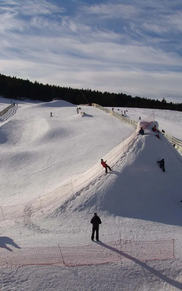 Familles et enfants profitant d’un espace ludique enneigé pour la glisse et les jeux d’hiver.
