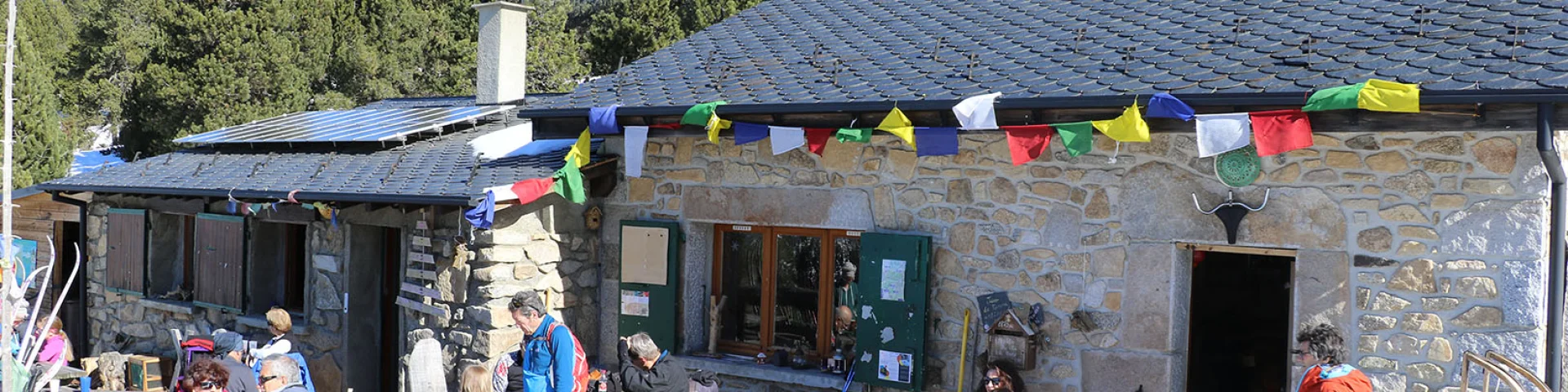 Refuge du Col del Torn à La Llagonne, ensoleillé, avec des visiteurs installés en terrasse.