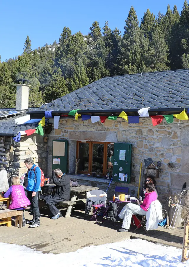 Refuge du Col del Torn à La Llagonne, ensoleillé, avec des visiteurs installés en terrasse.