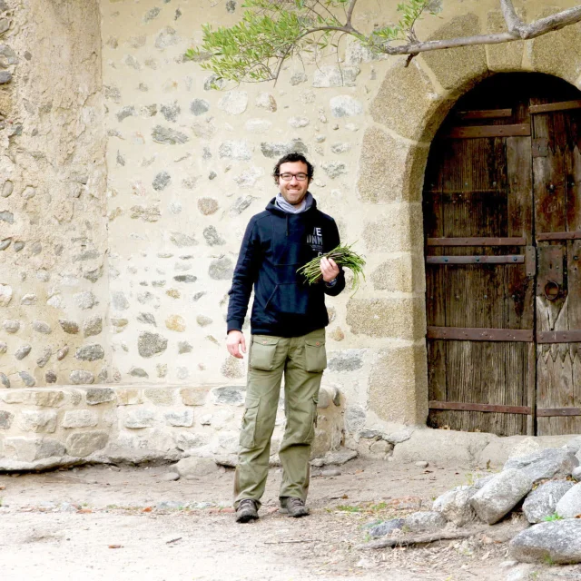 Personne tenant des asperges sauvages devant une église en pierre.