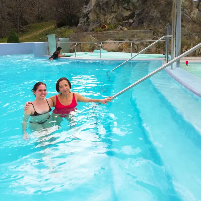 Emma et Gloria profitent du bassin extérieur des Bains de Saint-Thomas, entouré de roches et de nature, dans une eau thermale turquoise.