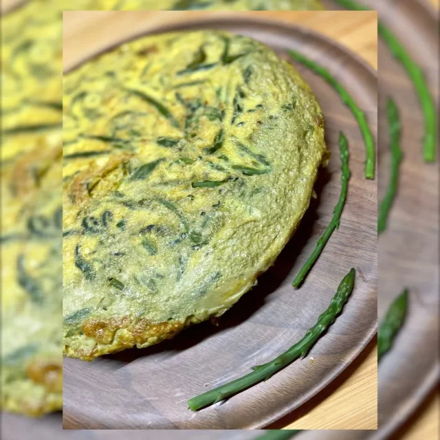 Omelette aux asperges sauvages servie sur une assiette en bois.