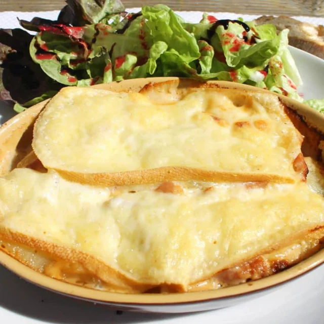Assiette de tartiflette gratinée au fromage, accompagnée d’une salade verte, servie en plein air au refuge des Bouillouses.