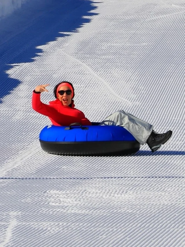 Personne descendant seule une piste enneigée sur une bouée bleue de snowtubing.