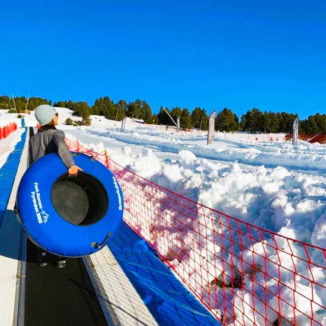 Personne montant sur un tapis roulant avec une bouée bleue de snowtubing dans la neige.