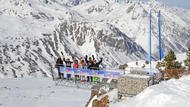 Groupe de skieurs debout sur la passerelle panoramique Le Pied dans le Vide à Porté-Puymorens, dominant les montagnes enneigées des Pyrénées.