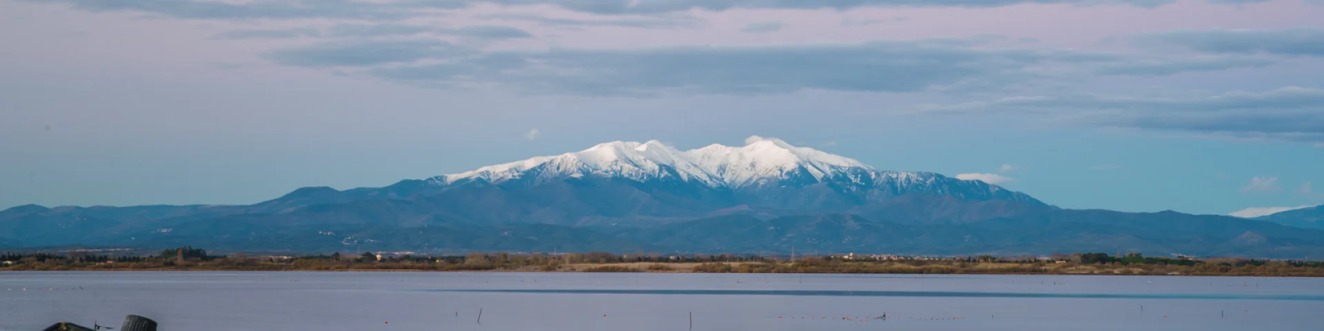 Deux barques bleues sur l’étang de Canet-Saint-Nazaire avec le Canigó enneigé en arrière-plan.