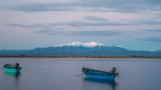 Deux barques bleues sur l’étang de Canet-Saint-Nazaire avec le Canigó enneigé en arrière-plan.