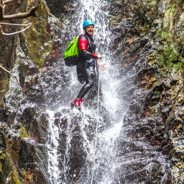 Personne descendant en rappel sous une cascade dans le canyon des Eaux Chaudes à Thuès-les-Bains.
