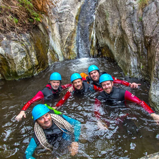 Groupe de personnes en combinaison et casque de canyoning dans une vasque rocheuse à Thuès-les-Bains.