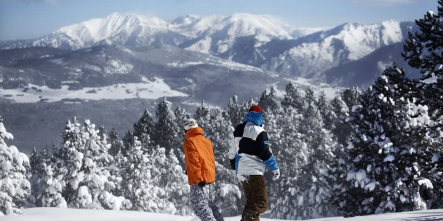 Deux snowboardeurs sur la piste de la Calme à Font-Romeu, avec une vue panoramique sur les montagnes enneigées des Pyrénées.