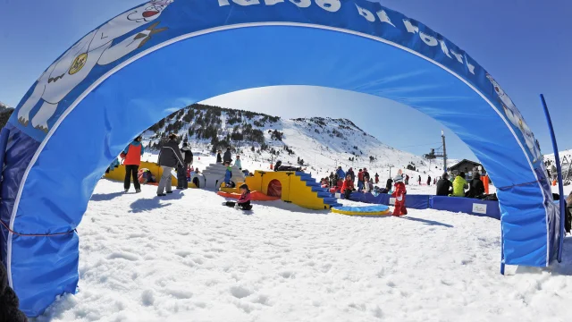 Enfants et familles jouant dans la neige à l’aire ludique Igloo de Porty, au pied des pistes de la station de Porté-Puymorens, sous un ciel bleu.
