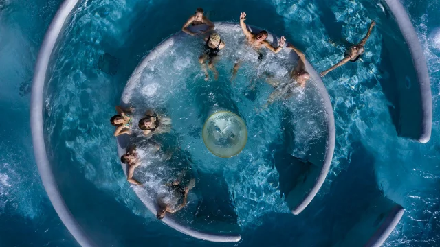 Vue aérienne de personnes profitant d’un bassin circulaire à jets d’eau dans le centre balnéo et spa Angléo aux Angles.