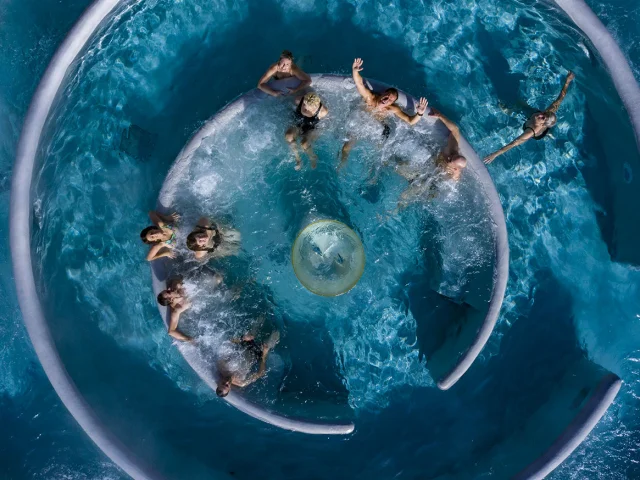 Vue aérienne de personnes profitant d’un bassin circulaire à jets d’eau dans le centre balnéo et spa Angléo aux Angles.
