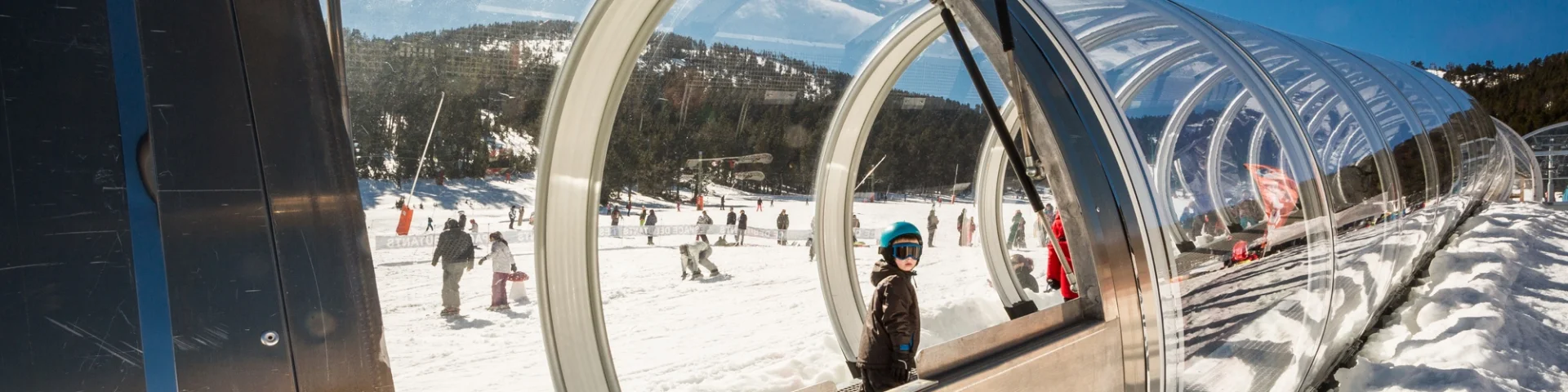 Enfant utilisant un tapis roulant couvert sur une piste de ski à Formiguères.