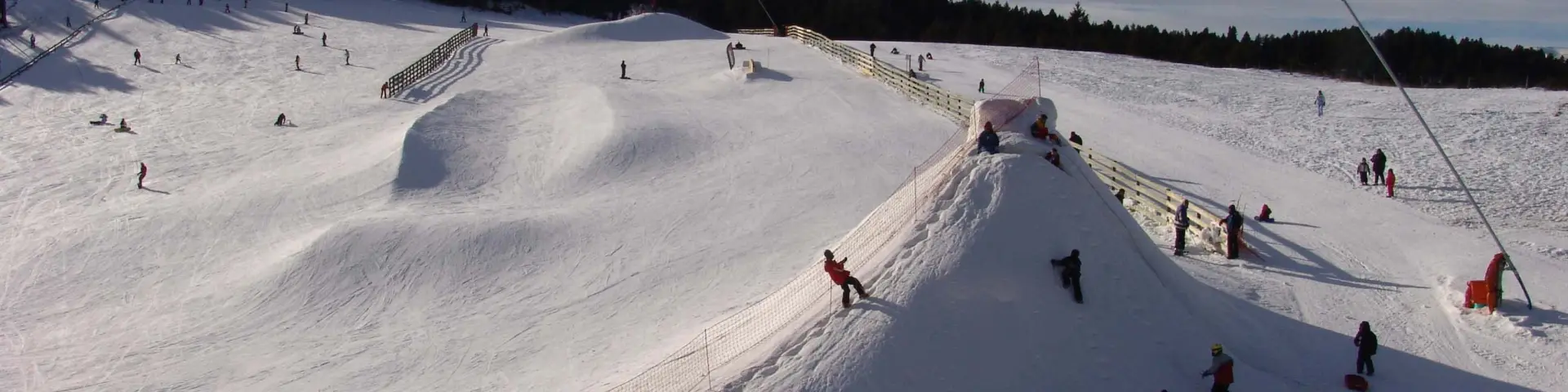 Familles et enfants profitant d’un espace ludique enneigé pour la glisse et les jeux d’hiver.