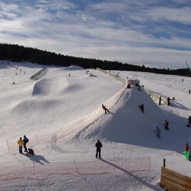 Familles et enfants profitant d’un espace ludique enneigé pour la glisse et les jeux d’hiver.
