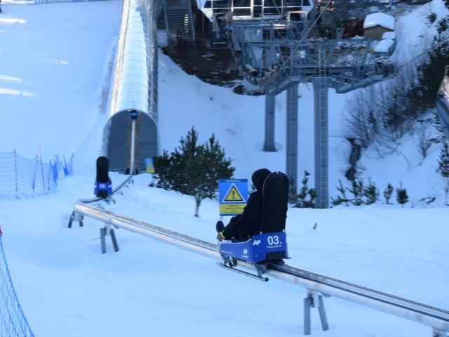 Personnes descendant une piste enneigée à bord de luges sur rail Lou Bac Mountain, à la station de ski des Angles.