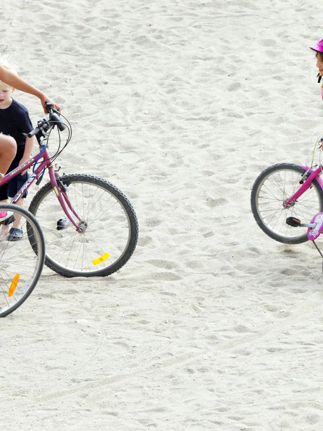 Famille avec des vélos arrêtée sur une zone sablonneuse en bord de mer.