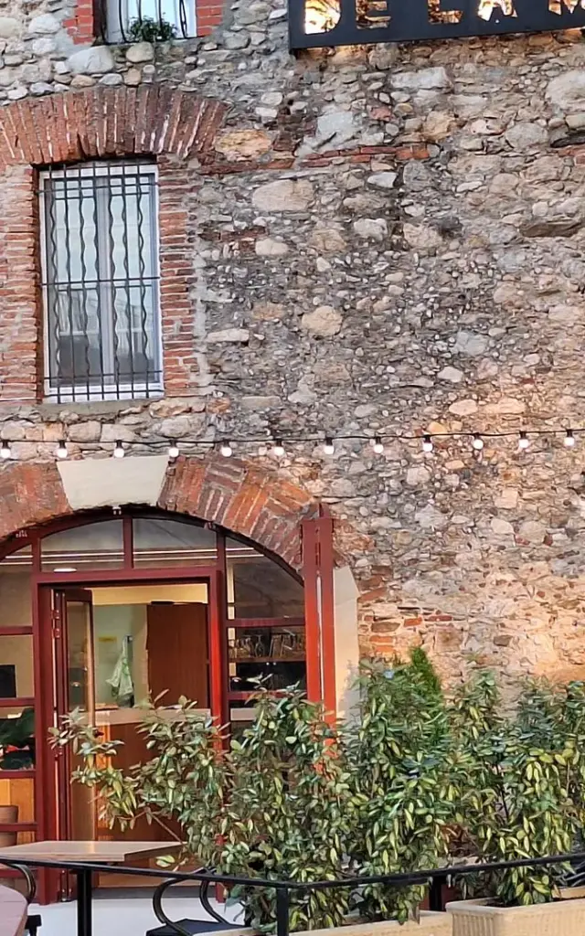 Façade en pierre du Relais de la Massane avec terrasse extérieure illuminée.