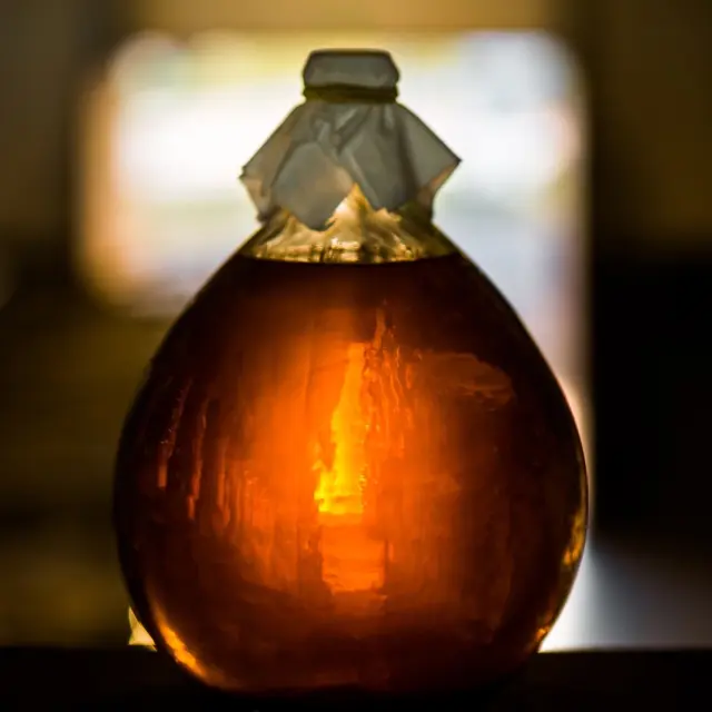 Bouteille en verre remplie d’un liquide ambré, éclairée en contre-jour.