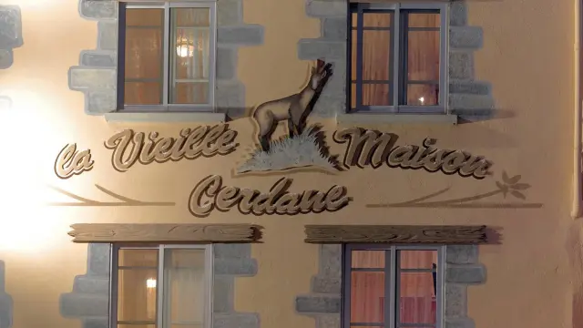 Façade d’un bâtiment avec deux fenêtres et une enseigne peinte représentant un animal et du texte décoratif.