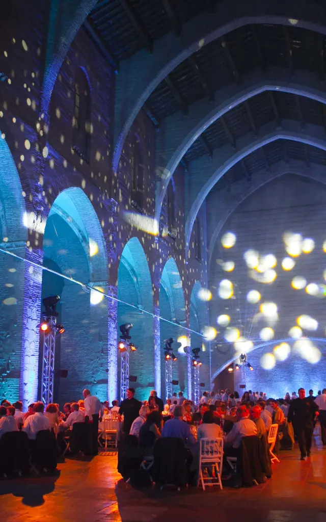 Dîner de gala dans la chapelle Saint-Dominique à Perpignan, éclairée de lumières bleues et dorées projetées sur les voûtes gothiques en brique.