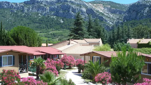 Hébergements entourés de lauriers-roses et de végétation, avec un massif rocheux en arrière-plan.