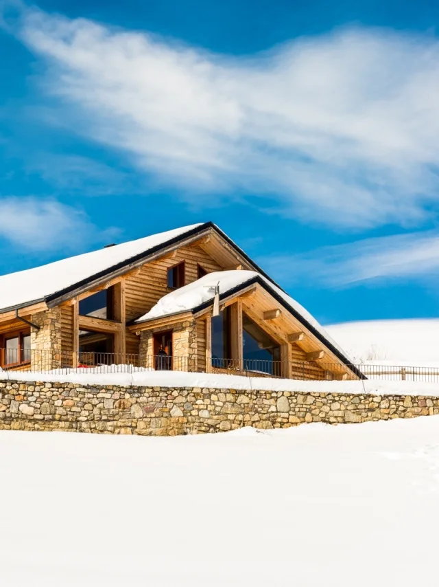 Grand chalet en bois et pierre à Saint-Pierre-dels-Forcats, entouré de neige sous un ciel bleu lumineux.