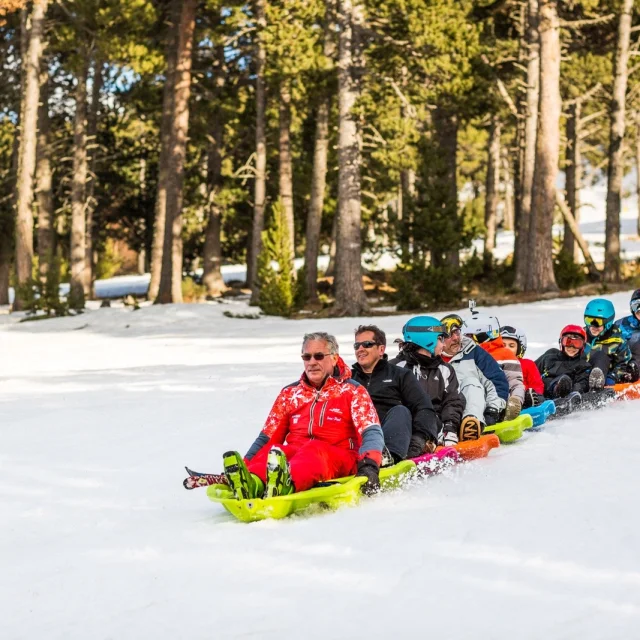 Groupe de personnes descendant une piste enneigée à Eyne Cambre d’Aze en snakeluge, pilotée par un moniteur de l’École du Ski Français.