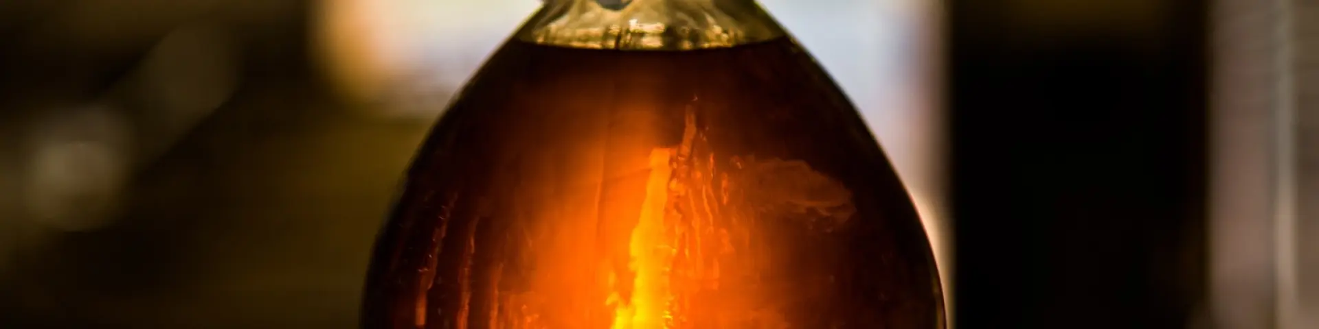 Bouteille en verre remplie d’un liquide ambré, éclairée en contre-jour.