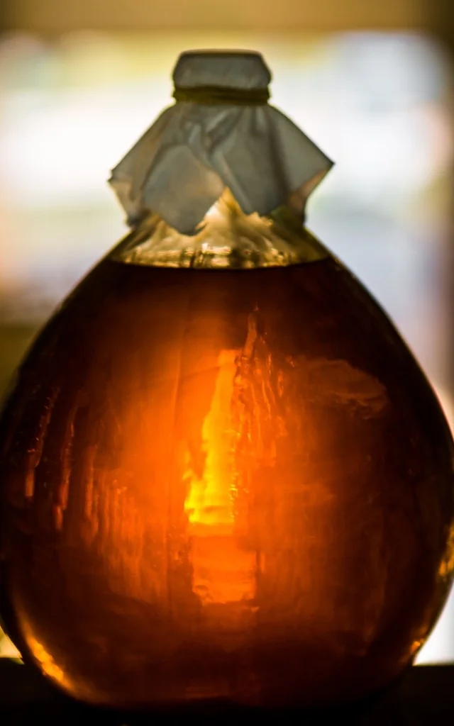 Bouteille en verre remplie d’un liquide ambré, éclairée en contre-jour.