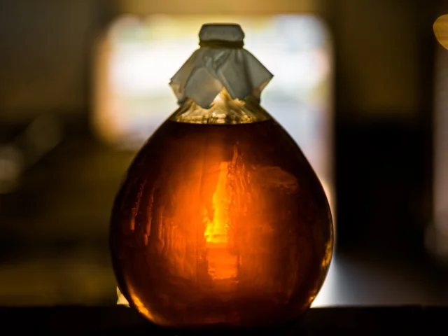 Bouteille en verre remplie d’un liquide ambré, éclairée en contre-jour.