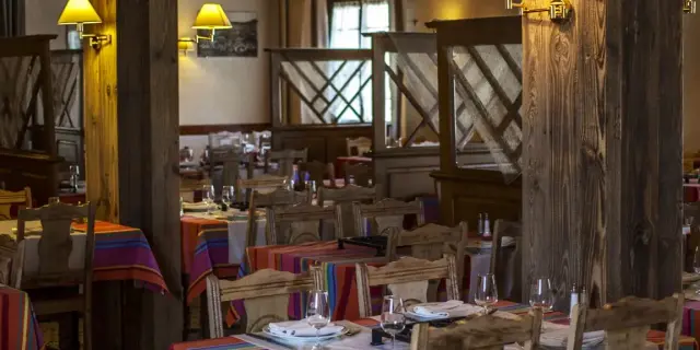 Salle de restaurant avec tables dressées et nappes colorées dans un décor en bois chaleureux.